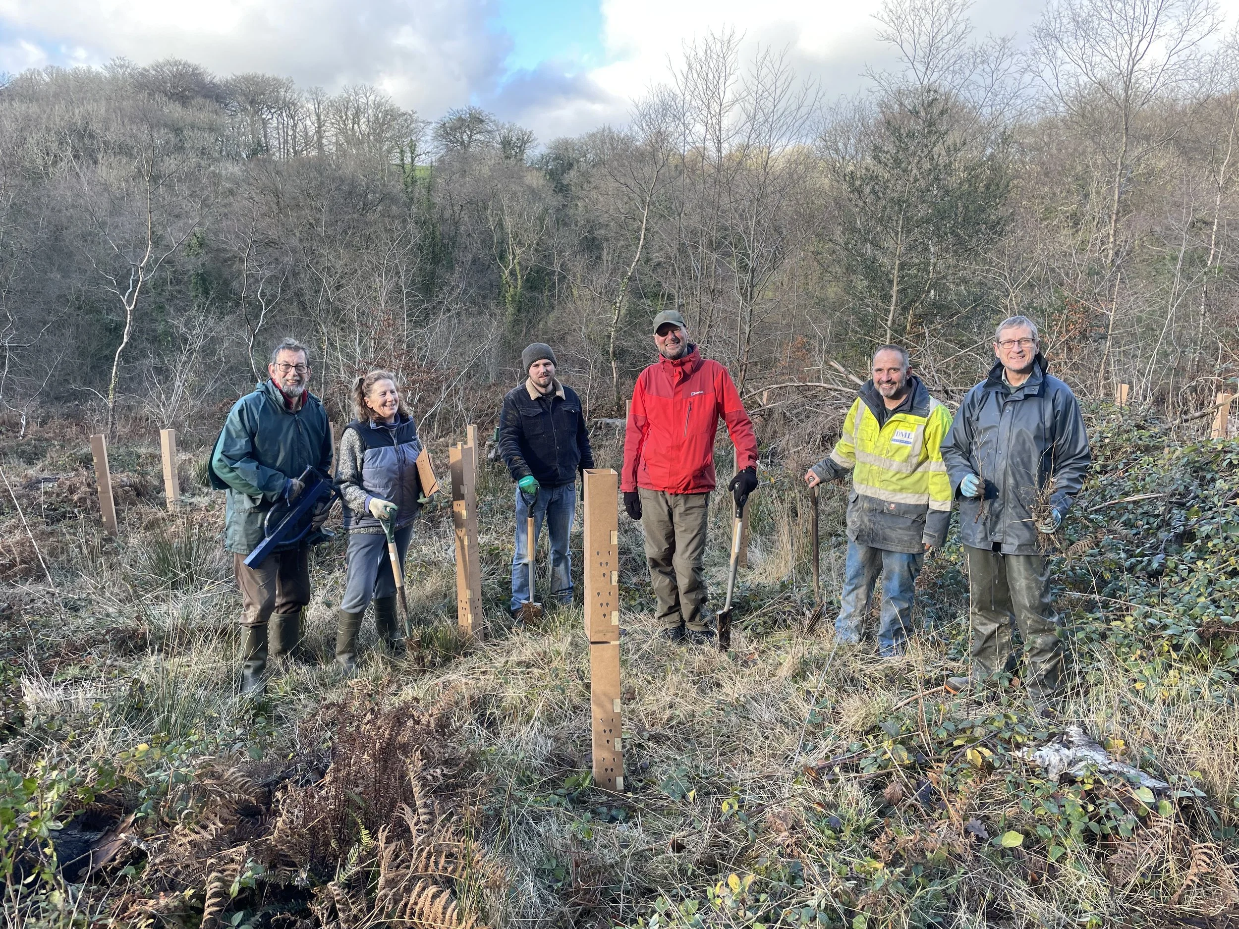 Group of people outdoors planting trees on a hillside